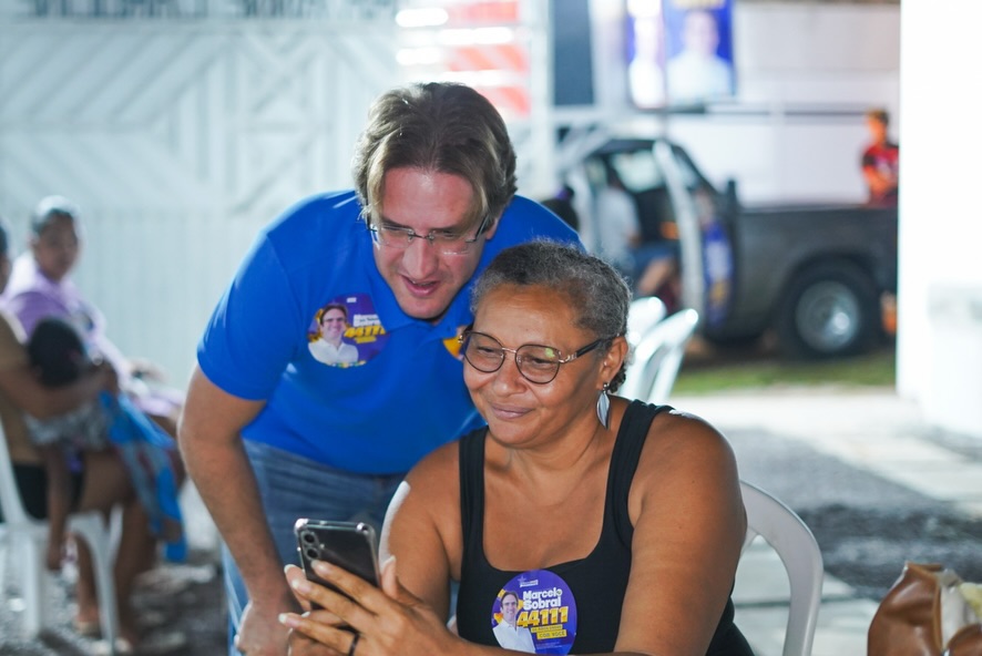 Marcelo Sobral observa o celular ao lado de uma moradora durante o encontro